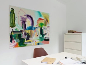 Kunstfotografie: Hellbunte Malerei von Künstler Fahar im Büro an der Wand hinter einem Schreibtisch